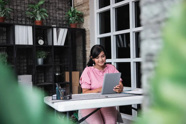 Jonge zakenvrouw zitten met haar tablet in het kantoor — Stockfoto