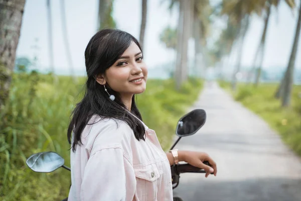 Donna in sella al suo scooter in strada di campagna tropicale — Foto Stock