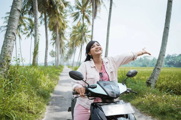妇女骑她的摩托车在热带乡村公路 — 图库照片