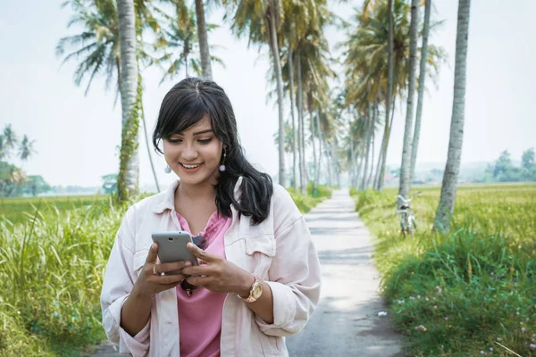 Vrouw met behulp van de mobiele telefoon buiten onder kokosnoot boom — Stockfoto