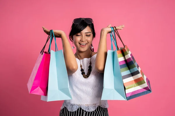 Mulher com sacos de compras sobre fundo rosa — Fotografia de Stock