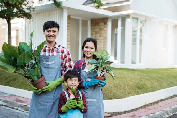 Eltern mit Sohn halten einen Topf voller Pflanzen und lächeln gemeinsam in die Kamera — Stockfoto