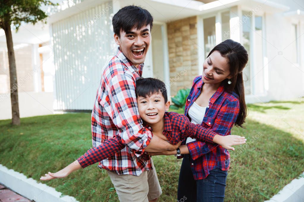 asian family with kid portrait in front of their house