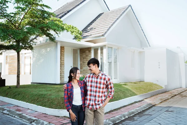 Asian couple standing in front of their new house — Stock Photo, Image