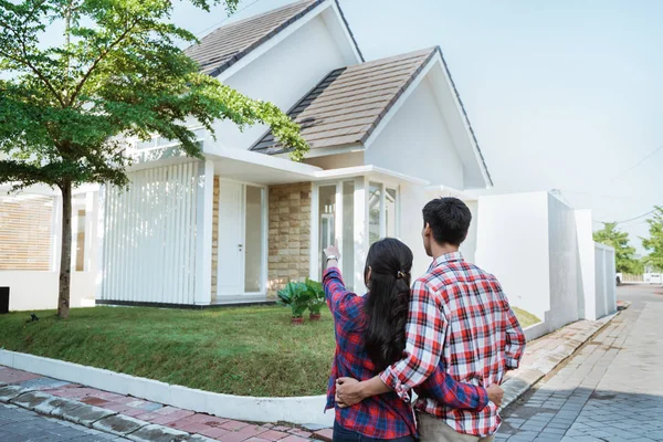 Joven pareja de pie en frente de su nueva casa — Foto de Stock