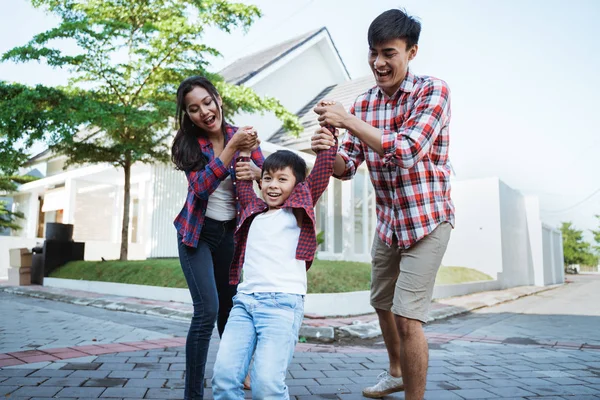 Eltern mit Kind genießen das gemeinsame Spielen vor ihrem neuen Haus — Stockfoto