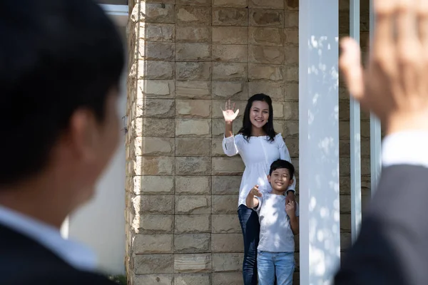 father waving goodbye to his family before going to work