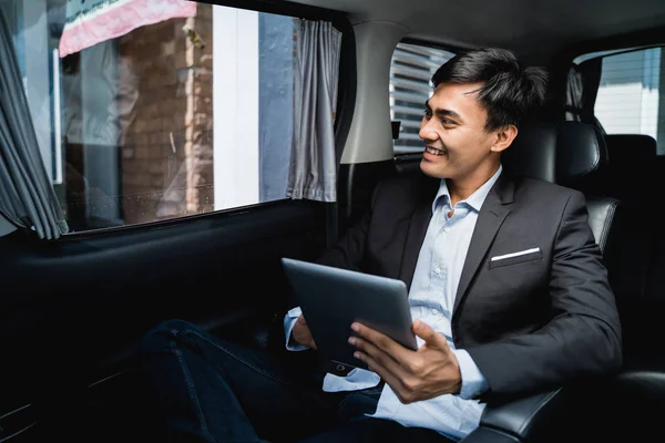 Executive using tablet while in the car on his way to the office — Stock Photo, Image