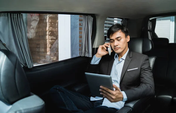 Businessman calling by phone and using tablet  in the car — Stock Photo, Image