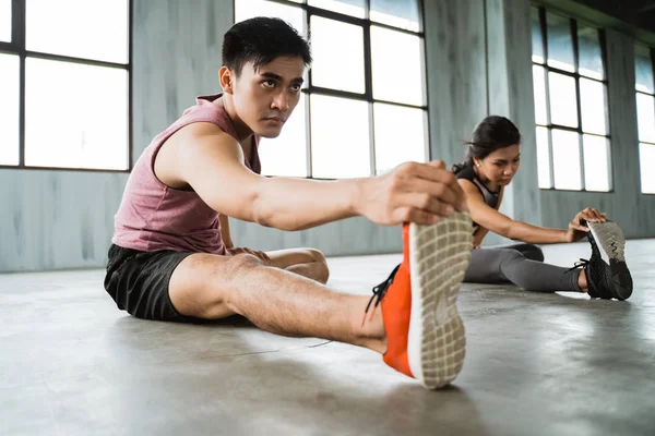 Asiático joven hombre haciendo piernas estiramiento antes núcleo ejercicio —  Fotos de Stock