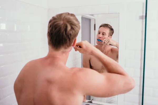 Τόπλες μυς άνθρωπος βουρτσίζει τα δόντια του μπροστά από τον καθρέφτη — Φωτογραφία Αρχείου