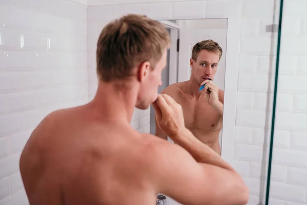 Adulto músculo hombre cepillarse los dientes en el baño —  Fotos de Stock