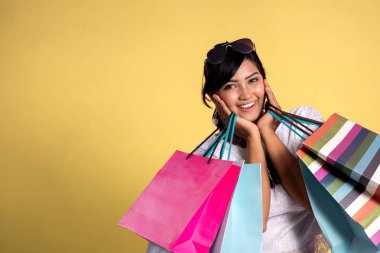 Sarı arka plan üzerinde alışveriş çantaları ile kadın