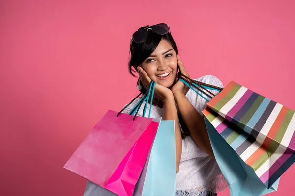 Kvinna med shoppingkassar över rosa bakgrund — Stockfoto