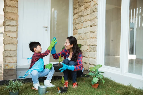 Madre e hijo highfive mientras jardinería juntos en casa — Foto de Stock
