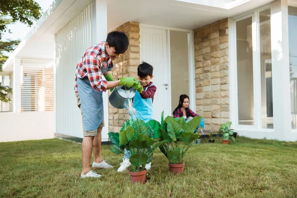 Père et fils arrosant une plante devant leur maison ensemble — Photo