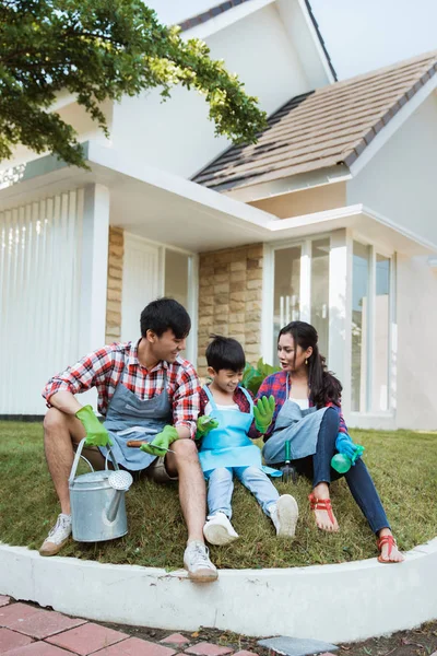 Familia y niño sentado en una hierba en su jardín de la casa después de la jardinería — Foto de Stock