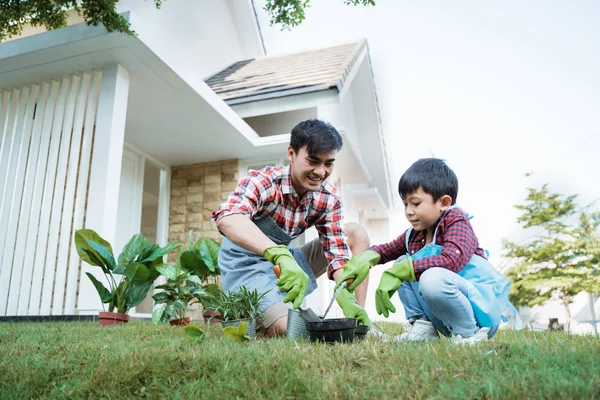 happy asian daddy and son gardening at his house garden