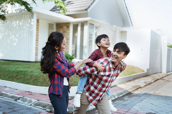 father piggyback ride with his son in front of the house