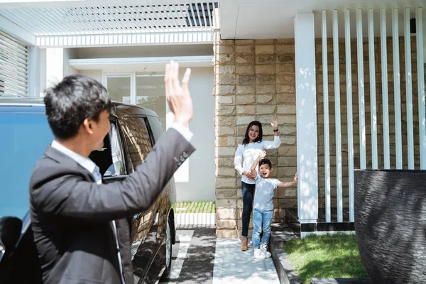 husband waving goodbye to his family before going to work