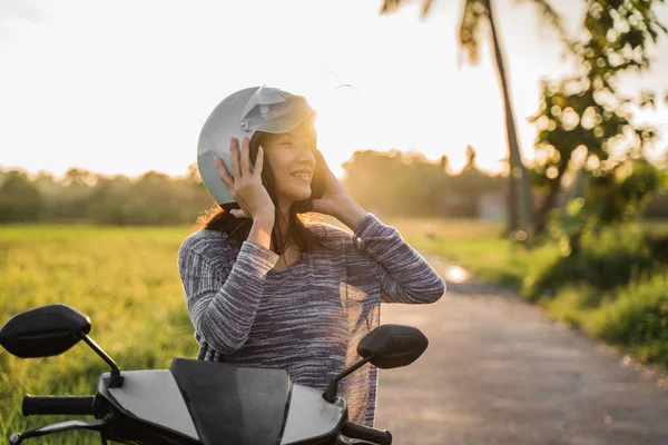 Mujer vistiendo y sujetar su casco mientras monta —  Fotos de Stock