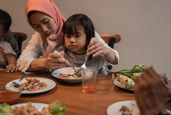 Musulmán mamá comer con su hija sentado en regazo —  Fotos de Stock