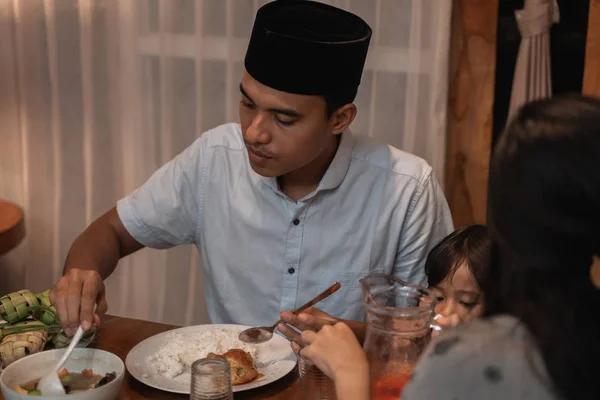 Young muslim man eating dinner with family — Stock Photo, Image