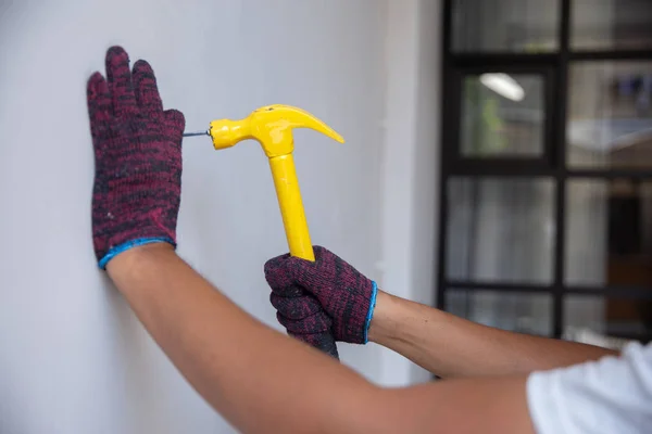 Hände aus nächster Nähe mit Handschuhen, die einen Nagel hämmern — Stockfoto