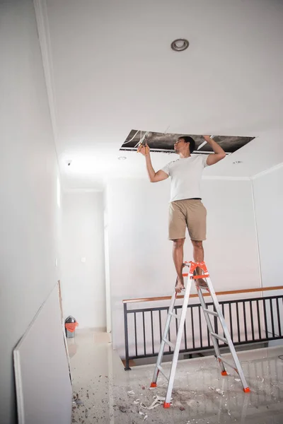 Мужчина чинит сломанный потолок — стоковое фото