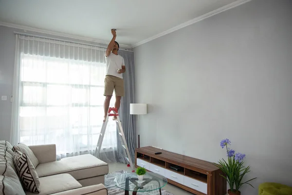Άνθρωπος χρησιμοποιώντας μια σκάλα για να εγκαταστήσετε τα φώτα — Φωτογραφία Αρχείου