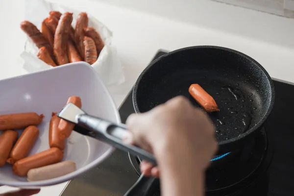 Руки с помощью щипцов для жарки колбас — стоковое фото