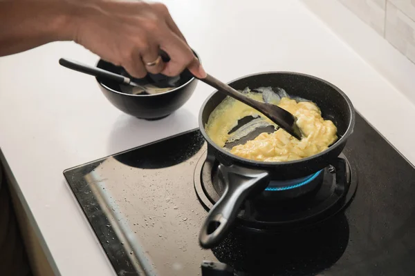 Mãos segurando espátula para fritar ovos mexidos — Fotografia de Stock