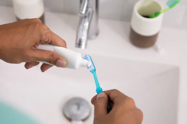 Mano apretando la pasta de dientes al cepillo — Foto de Stock