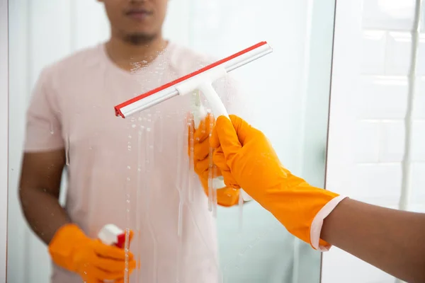 Człowiek wycierać lustro za pomocą narzędzia do czyszczenia — Zdjęcie stockowe