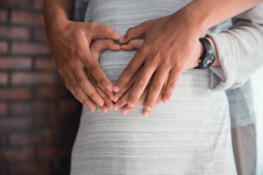 çift el hamile karın üzerinde kalp şekli yapma