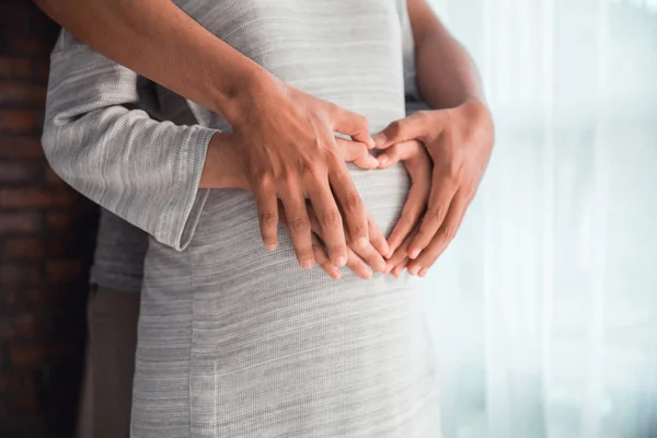 Couple hand making heart shape on pregnant belly — Stock Photo, Image