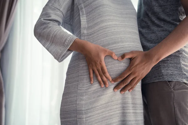 Paare lassen Herz auf Schwangerschaftsbauch formen — Stockfoto