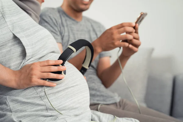 Fone de ouvido na barriga grávida ouvindo música clássica — Fotografia de Stock