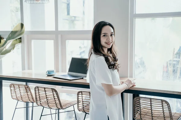 Aziatische vrouw glimlachend terwijl ze zelf in Café werkte — Stockfoto