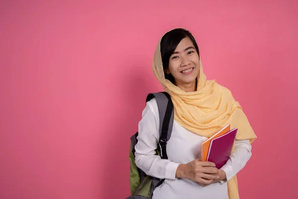 happy young muslim student smiling over pink background