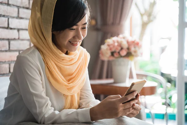 Moslim vrouw met behulp van mobiele telefoon thuis vergadering — Stockfoto