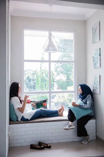 Μουσουλμανική γυναίκα και Ασιάτης φίλος κάθεται δίπλα στο παράθυρο — Φωτογραφία Αρχείου