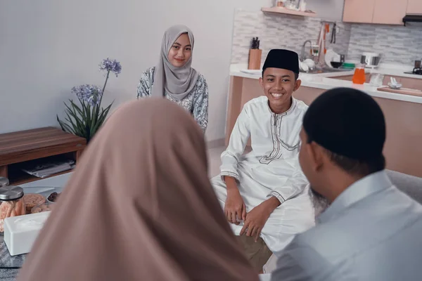 Мусульманская семья и друг разговаривают друг с другом, сидя на диване — стоковое фото