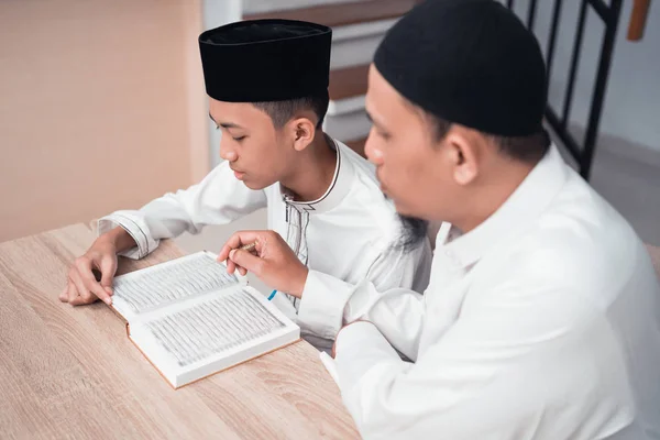Pai muçulmano ensinando seu filho a ler o Alcorão — Fotografia de Stock