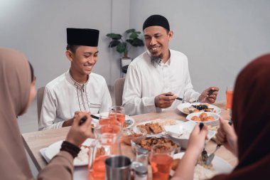 Müslüman baba ve oğul birlikte yemek yiyorlar.