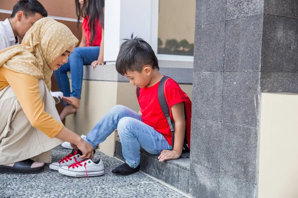 Ayudar a su hijo a ponerse los zapatos —  Fotos de Stock