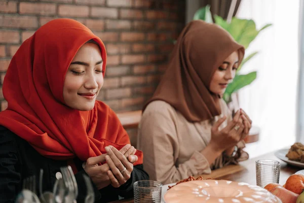Hiyab mujeres rezan juntas antes de las comidas —  Fotos de Stock