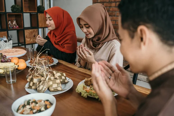 Hiyab mujeres y un hombre rezan juntos antes de las comidas —  Fotos de Stock