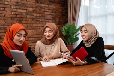 Üniversite öğrencisi grubu, dijital tablet ile arkadaşlar ve bir kitap taşıyan