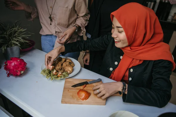 Asian woman hijab plating a cuisine with tomato